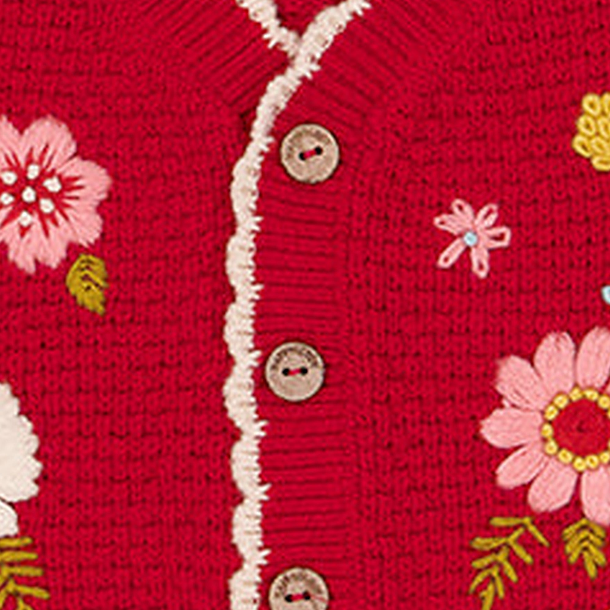 Close detail of hand embroidered flowers on a Happyology knitted vest